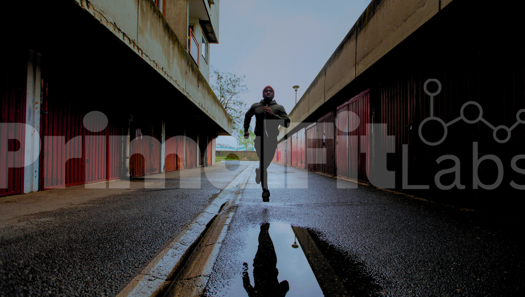 Person running on a wet road with a building in the background, featuring 'PrimalFit Labs' branding.